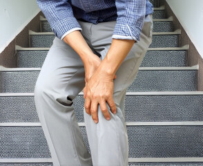 階段で膝の痛みに苦しむ中年男性