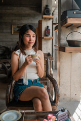 A young woman sits in a stylish cafe, savoring a cup of coffee, surrounded by modern decor and natural light.