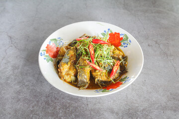 Spicy Thai fish curry with herbs, kaffir lime leaves and red chili, in enamel bowl