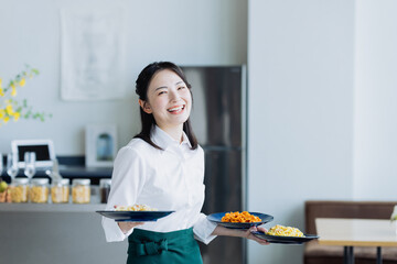 カフェで料理を運ぶ若い女性の店員