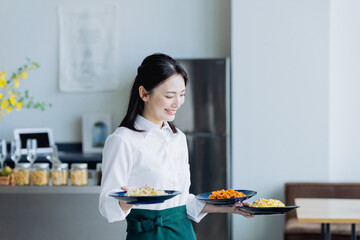 カフェで料理を運ぶ若い女性の店員