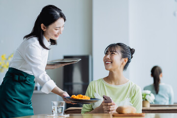 カフェで料理を配膳する若い女性