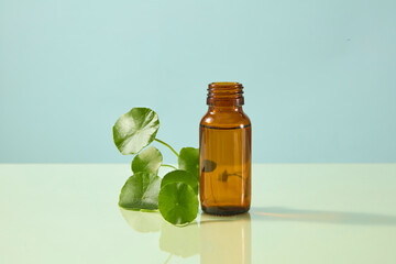 Close-up amber skincare bottle with Centella leaves on blue background. Simple natural ingredient-inspired composition for beauty visuals.