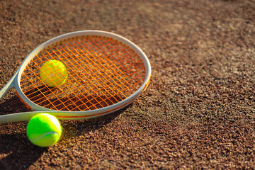 Yellow tennis ball lying on rocket at outdoor summer sunny court ground closeup