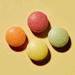 Obraz premium Four colorful, circular candies with textured surfaces lie on a solid yellow background