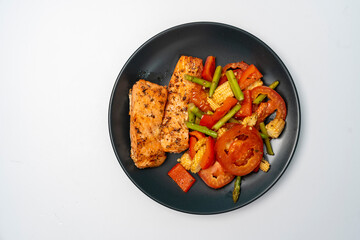 Grilled or Fried salmon steaks with fresh vegetables on plate isolated white background.