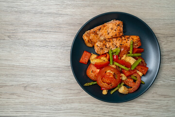 Grilled or Fried salmon steaks with fresh vegetables on plate. Top view on wooden table.