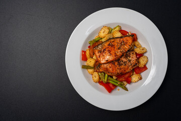 Grilled or Fried salmon steaks with fresh vegetables on plate isolated black background. Top view.