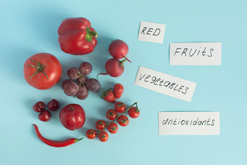 Red fruits, vegetables and berries, as well as inscriptions on white paper in close-up on a light background top view	