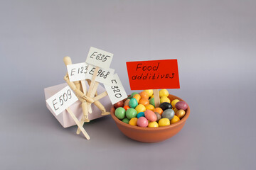 Dishes filled with colored granules of food additives and a doll holding signs with inscriptions