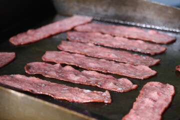 Cooking Bacon on a grill camping in the mountains