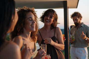 Friends enjoying drinks and laughing together at sunset party