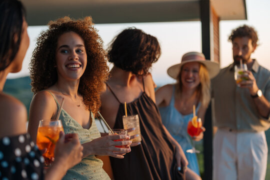 Friends enjoying cocktails at sunset party on a rooftop