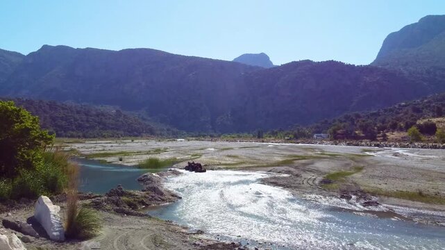 Footage showcasing the stunning natural beauty of Saklikent National Park in Turkey, featuring the flowing Esen &Ccedil;ayı river also known as Xanthos River through a wide, rocky riverbed with majestic moun
