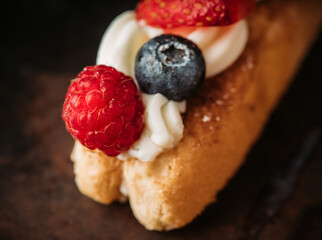 Tiramisu-style dessert with savoiardi, cream cheese and berries on dark background. Sweets and desserts.