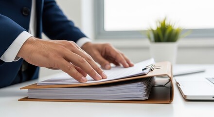 Businessman hands organizing documents on a clipboard and stack of papers on white office desk with laptop and plant