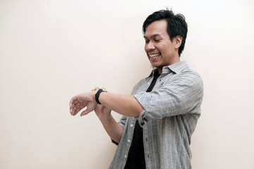 Southeast Asian man wearing flannel shirt holding a watch and smiling happy expression, on white...