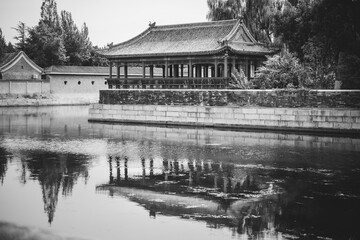 Black and white photo of traditional architecture at The Palace Museum, Beijing, reflected in still...