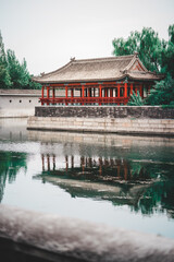A serene scene from The Palace Museum in Beijing, showcasing an ancient structure with a reflection...