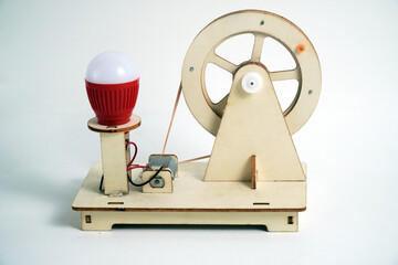 A small, handmade wooden generator with a light bulb, showcasing a simple mechanism with a flywheel and pulley.  Concepts of renewable energy, physics, science projects, and simple engineering.