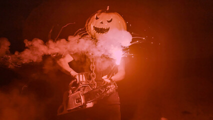 Halloween human pumpkin or Jack o lantern costume on a dark night with lots of smoke, a chainsaw,...