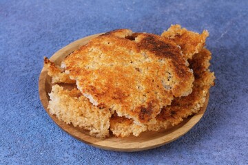 Crispy golden Korean scorched rice called nurungji served on wooden plate, traditional snack and side dish.