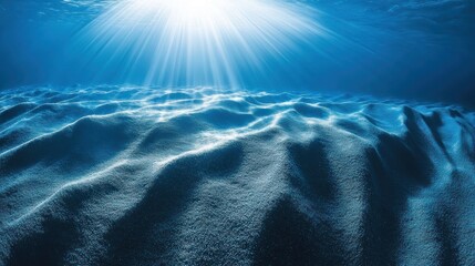 Sunbeams pierce the deep ocean floor, illuminating a textured, sandy seabed