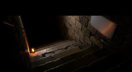 Dark stone staircase with a single lit candle casting shadows