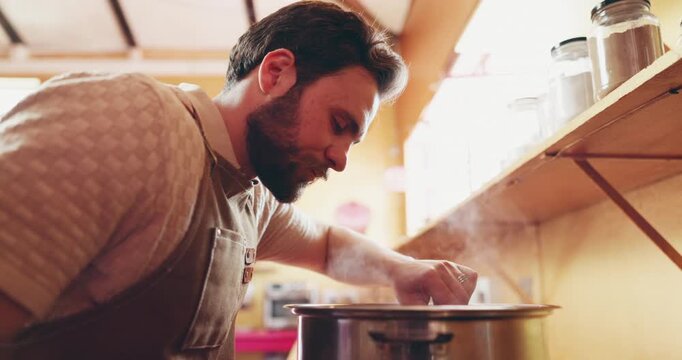 Cooking, smell and man by stove in kitchen with meal prep, for dinner, lunch and cuisine for small business. Food, culinary and person with aroma, ingredients and recipe in pot for catering service