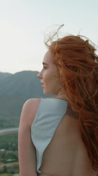 Slow motion vertical video redhead woman turning camera smiling moving hair face windy mountains cinematic lifestyle fashion natural authentic beauty freedom feminine