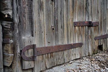 An iron bracket on an old wooden garage and barn door.