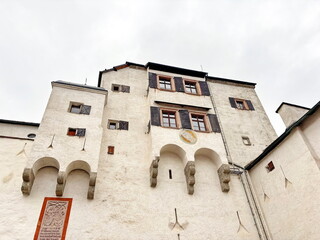 A view of the snow-white walls of the central facade of the church of St. George in Hohensalzburg against a background of a cloudy summer sky.