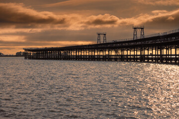 Fototapeta premium Pier of the Rio Tinto Company at sunset (Huelva, Spain). Rio Tinto mineral loading pier declared an Asset of Cultural Interest. Pier at sea.