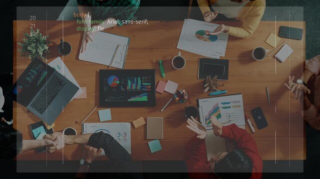An overhead view of a diverse team collaborating in a meeting, showcasing coding on screens and engaged discussion, highlighting teamwork and productivity. Raster
