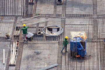 Construction workers wearing safety vests and helmets working on a building framework.