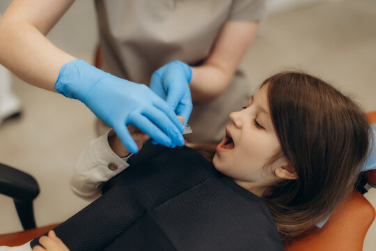 Dentist preparing fluoride varnish treatment for little girl in dental clinic