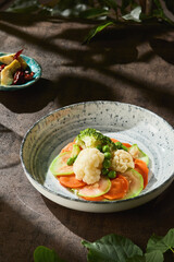 Steamed broccoli, zucchini, carrot, cauliflower with bright rustic lighting, overhead composition