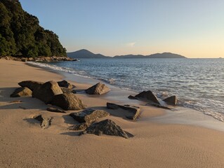 Beach with rocks and mountains during sunset