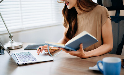 Closeup view of young professional businesswoman writing his idea concepts on notebook while working on his project at office