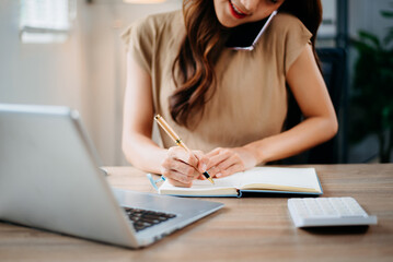 Closeup view of young professional businesswoman writing his idea concepts on notebook while working on his project at office