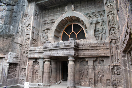 elaborately carved entrance of cave19 at ajanta caves, this buddhist chaitya hall, dating to the 5th century CE, features a large horseshoe shaped window, intricate facade sculptures, and standing bud