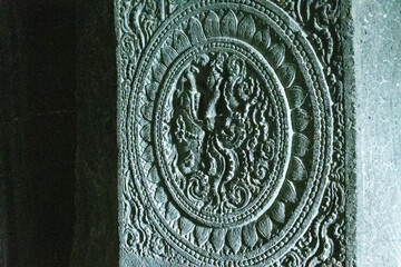 closeup view of an intricately carved circular medallion on stone at ajanta caves, detailed bas-relief features mythological motifs and ornamental floral patterns