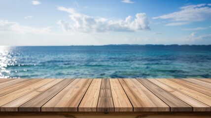 Empty wooden deck table top extending toward a blurred turquoise tropical ocean under a bright sunny blue sky.