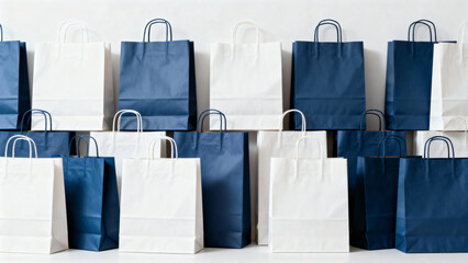Arrangement of white and navy blue paper shopping bags in a grid pattern against a neutral...