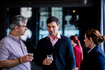 Business networking event with diversity professionals interacting in a rooftop lounge, reflecting corporate culture, strategy sharing, and the value of collaboration.