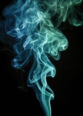 Obraz premium Abstract swirling blue and green smoke wisps rising against a dark background