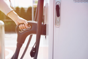 Hand is holding fast electric car charger green energy environment friendly driving vehicle station. Modern transport fuel of future. Minimal design power unit	
