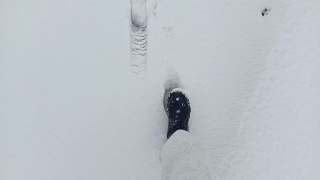 top view Women's feet walk on the snow and step on footprints in the snow. A woman follows footprints in the snow. The concept of missing a person in the mountains, in winter