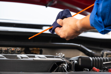 A mechanic's hand checks the engine oil level and he is about to change the engine oil	