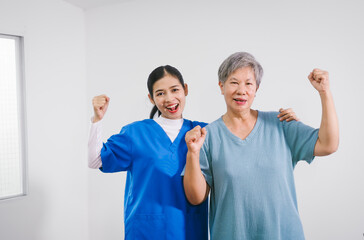 An Asian female nurse provides caring home care to an elderly woman, assisting with arm movement exercises, physical therapy,and rehabilitation to improve joint function, strength,overall well-being